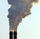 Steam and exhaust rise up from a smokestack of ... 