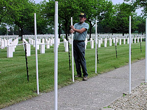 Steve Johnson, a Ft. Snelling cemetery worker, makes sure each pole is straight. The poles will hold flags for Memorial Day.