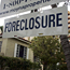 A foreclosure sign hangs in front of a home in ...