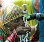 An elderly Indian woman drinks water from a ... 