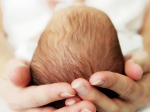 A mother holds a baby's head 