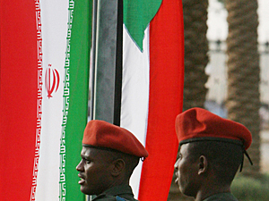 Sudanese soldiers walk by their national flags 
