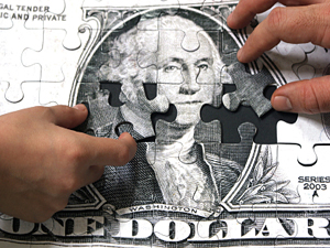 A child and an adult piece together a money puzzle 