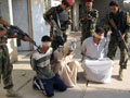 Iraqi soldiers guard blindfolded suspects