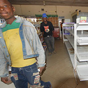Shoppers walk past empty shelves in Mabvuku, ... 
