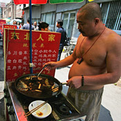 A cook prepares food at a street-side food ... 