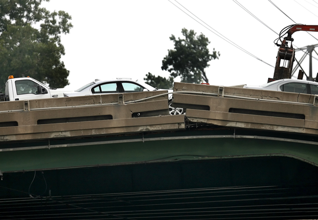 Cars sit on remains of the Interstate 35W bridge after it collapsed during evening rush hour August 1, 2007 in Minneapolis. The eight lane steel and concrete bridge, which was undergoing repair work, broke apart dropping at least 50 vehicles into the Mississippi river.