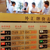 Customers stand in front of a currency ... 