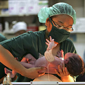 A medical intern weighs a newborn. 