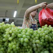 A woman buys grapes at a market in Beijing. 
