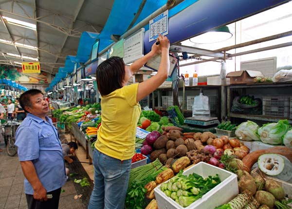 
                A government food administrator watches a vegetable vendor correct her prices at a Beijing market.
                                    (Teh Eng Koon/AFP/Getty Images)
                                