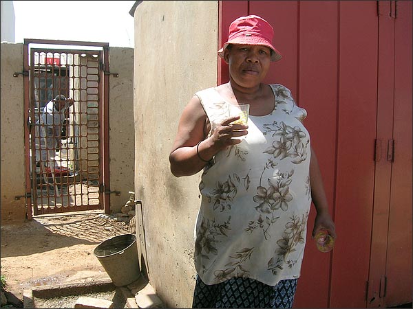
                Zodwa Mokhosi stands in front of the tap in her back yard. She defied pressure to sign up for the prepaid water system, and now has the only tap in the neighborhood that won't be cut off. She lets her neighbors take water for free.
                                    (Gretchen Wilson)
                                