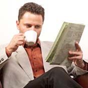 Man lounging on sofa with coffee and newspaper 