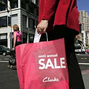 A shopper carries a bag advertising a sale. 