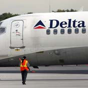 A worker helps guide a Delta Air Lines plane 