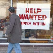 A man walks by a help wanted sign 