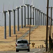 Car drives by wind turbines 