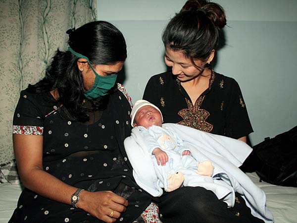
                American Karen Kim, right, holds her son, Brady, after his delivery by a surrogate mother at a clinic in Anand, India.
                                    (Sam Panthaky/AFP/Getty Images)
                                