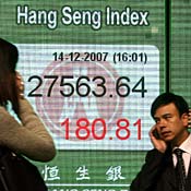 People walk past a Hang Seng Index board 