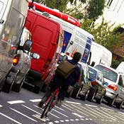 A cyclist rides through London traffic. 
