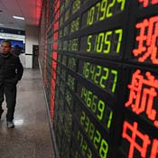 A Shanghai investor walks past a stock price board 