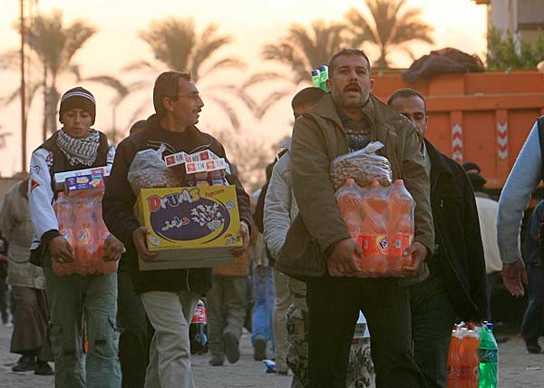 
                Palestinians from Gaza carry goods they bought in Rafah on the Egyptian side of the border after crossing from the Gaza Strip. Tens of thousands of Palestinians poured into Egypt today to stock up on goods because of an Israeli blockade, after militants blew up parts of the border with the Gaza Strip.
                                    (Khaled Desouki/AFP/Getty Images)
                                