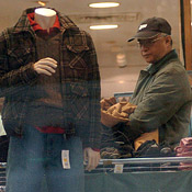 A man considers a shirt as he shops for clothes. 