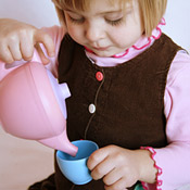 A girl plays with a tea set from Green Toys 