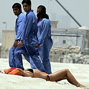 Workers glance at Jumeirah Beach sunbather 