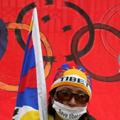 Tibetan demonstrator in front of Olympic flag 