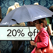 Woman with umbrella passes store display 