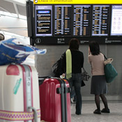 Passengers look over flight board at Heathrow 