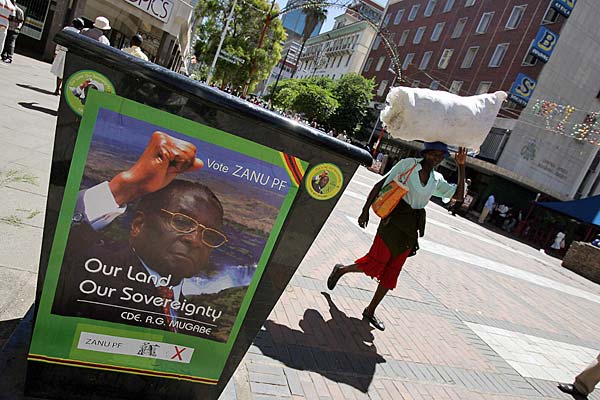 
                A woman walks past the poster of Zimbabwean President Robert Mugabe in Harare.
                                    (Alexander Joe/AFP/Getty Images)
                                