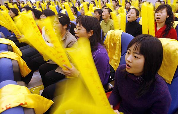 
                Punching the air with a pair of inflated yellow batons, employees at a dairy company in Beijing's eastern suburb chant their way through a two-hour coaching session aimed at preparing Chinese fans for the 2008 Beijing Olympics.
                                    (Peter Parks/AFP/Getty Images)
                                