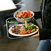 Student carries tray with organic vegetables 