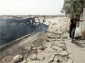 An Iraqi boy walks past a burning vehicle