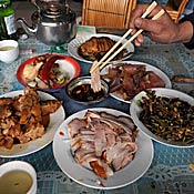 A slice of pork is placed into a dipping sauce 