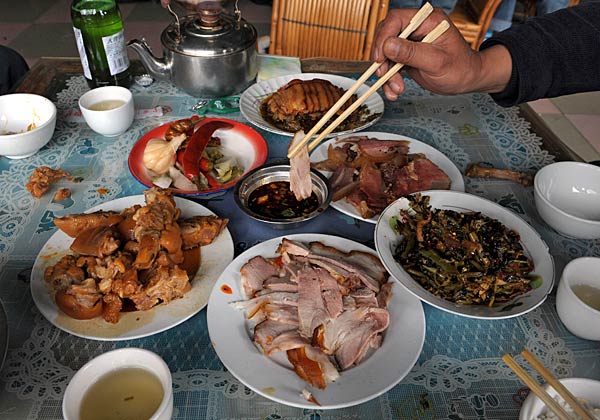 
                A slice of pork is placed into a dipping sauce on a table full of pork dishes on March 23, 2008 on the outskirts of Lijiang in southwest China's Yunnan province.
                                    (Frederic J. Brown/AFP/Getty Images)
                                