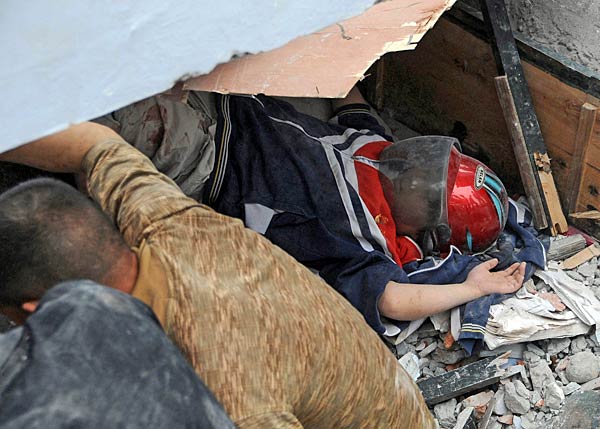 
                Rescuers try to get a boy (wearing a helmut for protection) out from the rubble of the collapsed Juyuan middle school where six children died in Dujiangyan, in southwest China's Sichuan province on May 12, 2008. FP/AFP/Getty Images)
                                    (AFP/Getty Images)
                                