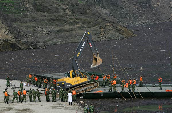 
                Chinese soldiers work with construction equipment at the Zipingpu Dam in Dujiangyan of Sichuan province, China. The dam was damaged by the 7.9 earthquake that hit the province, causing serious cracks. Some 2,000 troops have been sent to stabilize it.
                                    (China Photos/Getty Images)
                                
