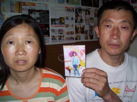 
                The husband of He Zhuoyin displays a photo of their daughter, 16, who is living alone in Sichuan province while they work in Shanghai.
                                    (Scott Tong / Marketplace)
                                