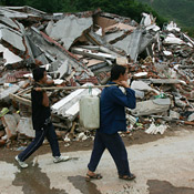 Earthquake survivors carry water past debris 