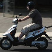 A man drives a scooter through the city. 