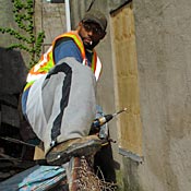 Shawn Chapman climbs a fence to access a property where he's boarding up a building.