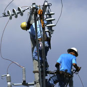 Linemen fix an electrical post 