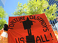 Protesters hold a sign in opposition of torture