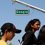 Pedestrians walk by Google street sign 