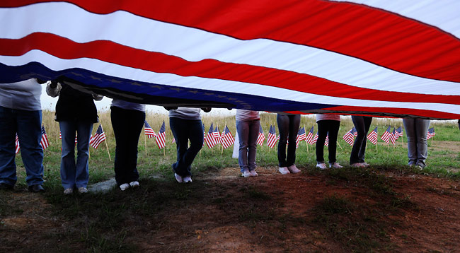 People unfurl a United States flag at the memorial site of United Airlines Flight 93 during a 9/11 memorial ceremony September 11, 2008 in Shanksville, Pa.
