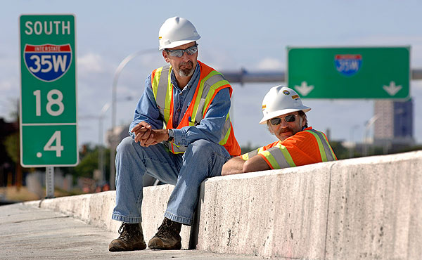 Workers from the Flatiron construction company rest on a guardrail and watch Monday morning's press conference.