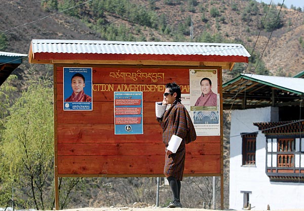 
                A Bhutanese man makes a cell-phone call as he stands beside an election campaign board displaying candidate posters in March 2008.
                                    (Deshakalyan Chowdhury/AFP/Getty Images)
                                